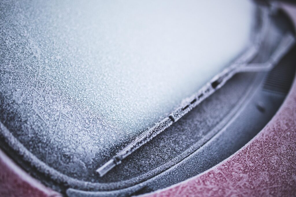 Frosted windshield with ice clearing or winter driving scene