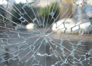 Shattered side window with safety glass on pavement, kept serious not graphic