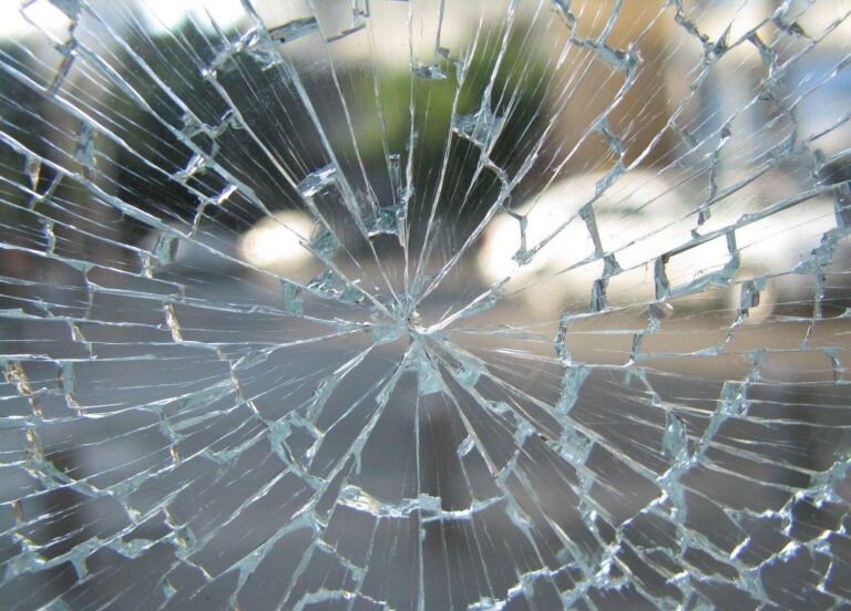 Shattered side window with safety glass on pavement, kept serious not graphic